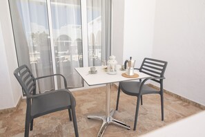 Un piccolo balcone con un tavolo, due sedie, una moka e una lanterna.