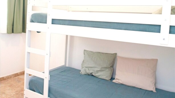A bunk bed with a green pillow and a white pillow, a green curtain, and a white wall. - Apartment Drago on Finca Falcon Cresta (Agüimes)