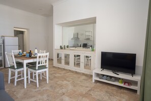A compact living space with a dining area, kitchenette, and a television on a stand. - Apartment Drago on Finca Falcon Cresta (Agüimes)
