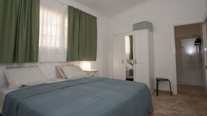 Una camera da letto con un letto, un armadio, un comodino e un bagno con doccia.