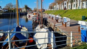 Un puerto deportivo con barcos amarrados, un muelle de madera y un edificio con techo rojo al fondo.