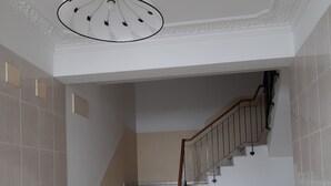 Una scala con corrimano, pareti bianche e una lampada a soffitto.