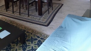 Un'area pranzo moderna con un tavolo e sedie in legno scuro, un grande specchio sopra il tavolo e un pensile in legno scuro sottostante.