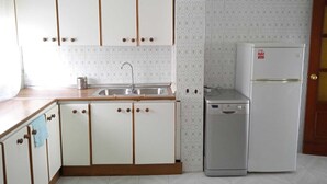 A kitchen with white cabinets, a stainless steel sink, and a white refrigerator.