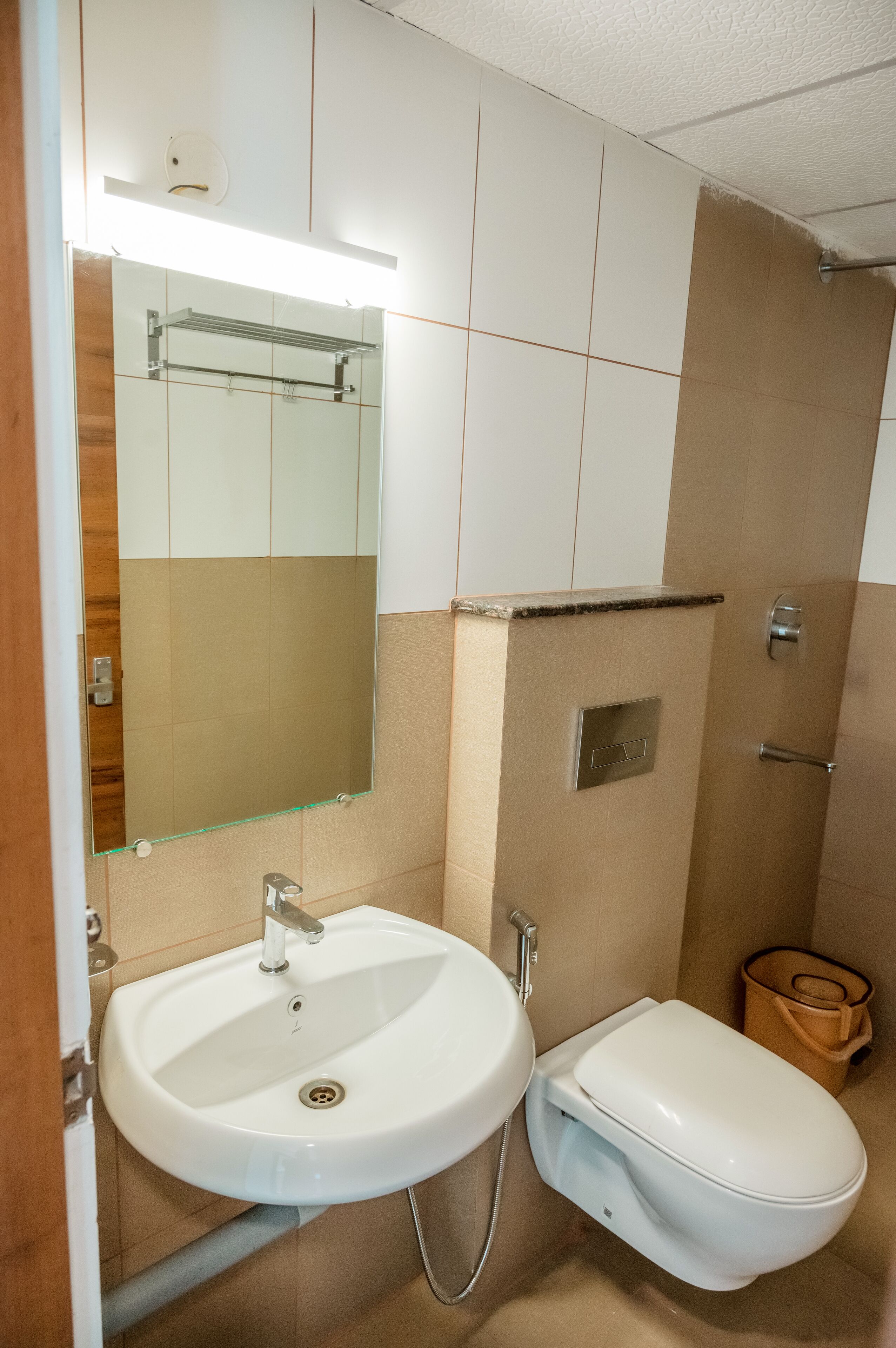A bathroom with a white sink, a toilet, a mirror, and a shower area.