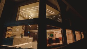 Un moderno vestíbulo de hotel con mostrador de recepción, zona de estar y una pantalla grande.