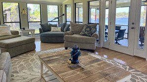 A spacious living room with a large window, a ceiling fan, and a view of the outdoors.
