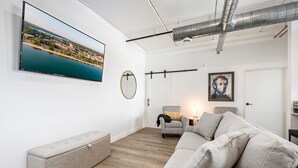 Una sala de estar moderna con un televisor de pantalla plana grande, un banco, un sofá y una silla.