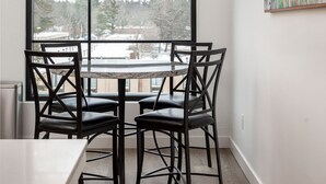 Un comedor con un ventanal grande, una lámpara moderna tipo candelabro y una obra de arte abstracta en la pared.