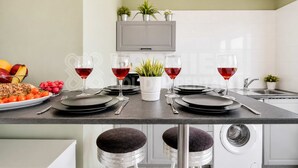 Una cocina moderna con una mesa de comedor preparada para cuatro personas, una lavadora y un televisor montado sobre la encimera.