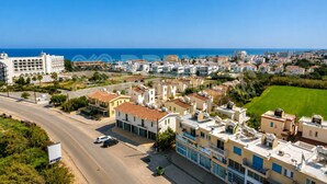 Zona residencial costera con edificios, una carretera y cielo azul despejado.