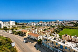 A coastal residential area with buildings, a road, and a clear blue sky.