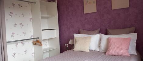 A bedroom with a bed, a wardrobe, and a nightstand.