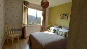 Ein Schlafzimmer mit einem Bett, einem Sessel, einem Fenster und einer Wand mit gerahmten Bildern.
