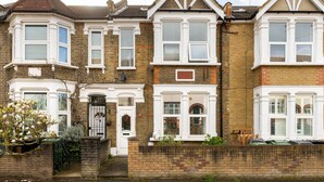 A row of terraced houses with bay windows, brick walls, and a front door with a small garden area. - Modern Apartment in Walthamstow (London)