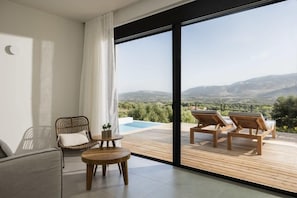 Un balcón con vistas a una piscina y montañas, amueblado con sillas y una mesa.