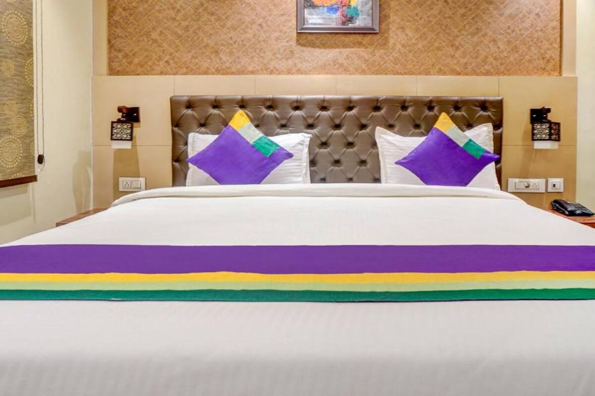 Ein Hotelzimmer mit einem großen Bett, einem gepolsterten Kopfteil und zwei Nachttischen mit Lampen.