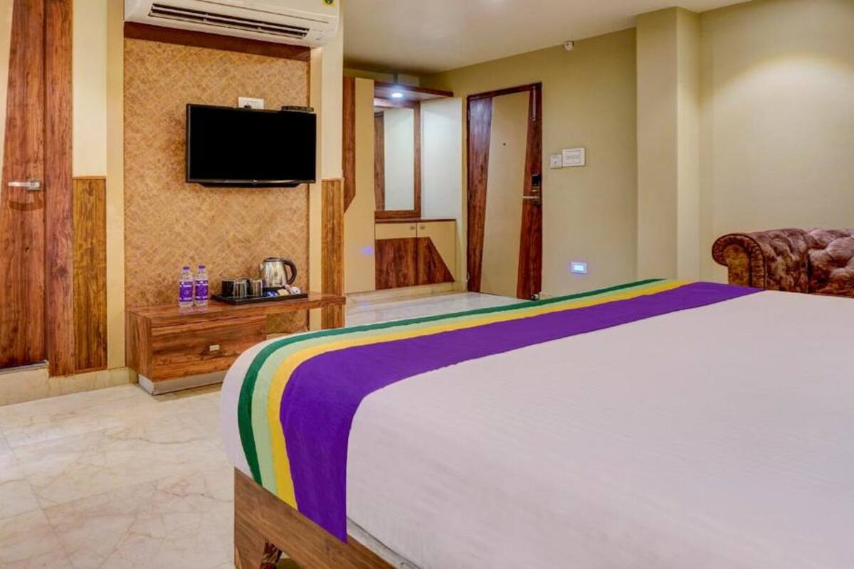 Ein Hotelzimmer mit einem Bett, einer Holzkommode, einem flachbildfernseher an der Wand und einem Spiegel.