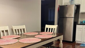Un comedor con una mesa de madera, cuatro sillas y un banco. Un candelabro cuelga sobre la mesa.