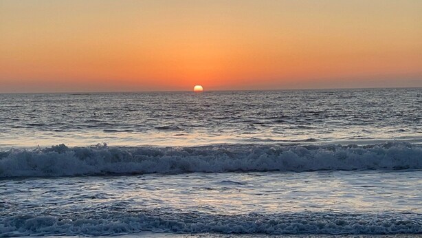 Atardecer sobre el océano con olas.