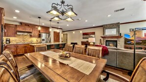 Una cocina amplia con armarios de madera, una isla central y un comedor con una gran mesa y sillas de madera.