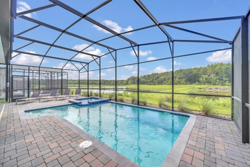 A covered outdoor swimming pool with a view of a green landscape.