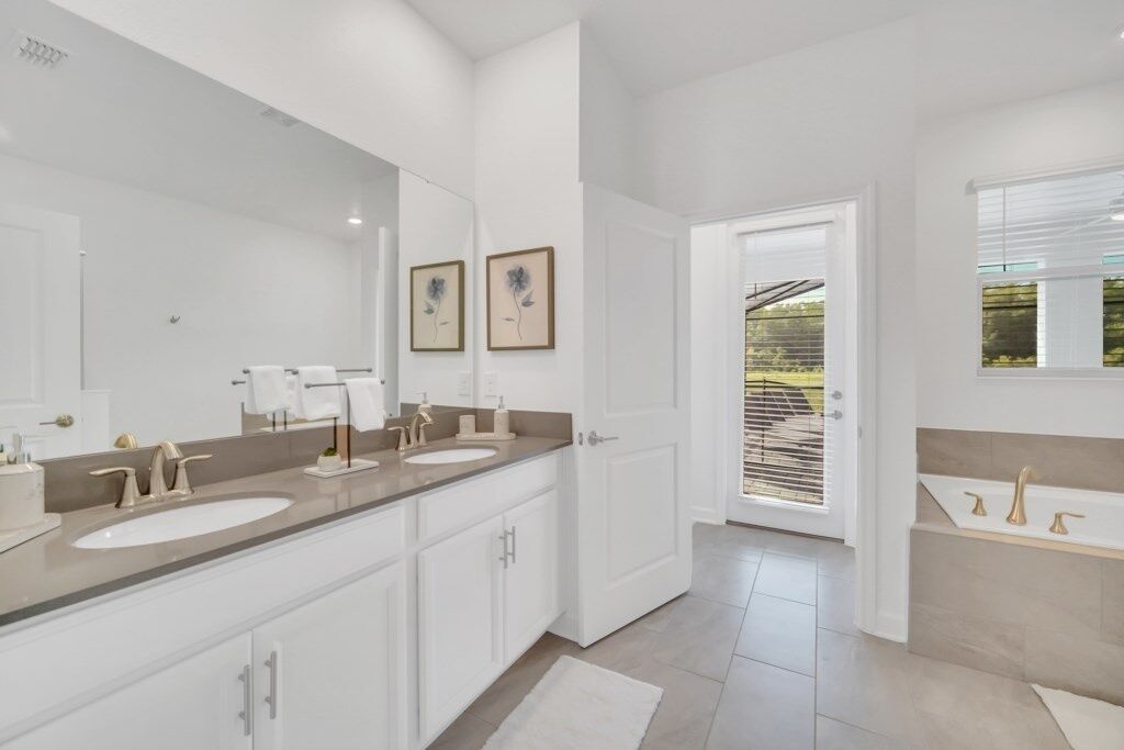 A modern bathroom with two sinks, a large mirror, and a door leading to a balcony.
