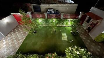 A well-lit courtyard with a small water feature, surrounded by plants and a tiled floor.