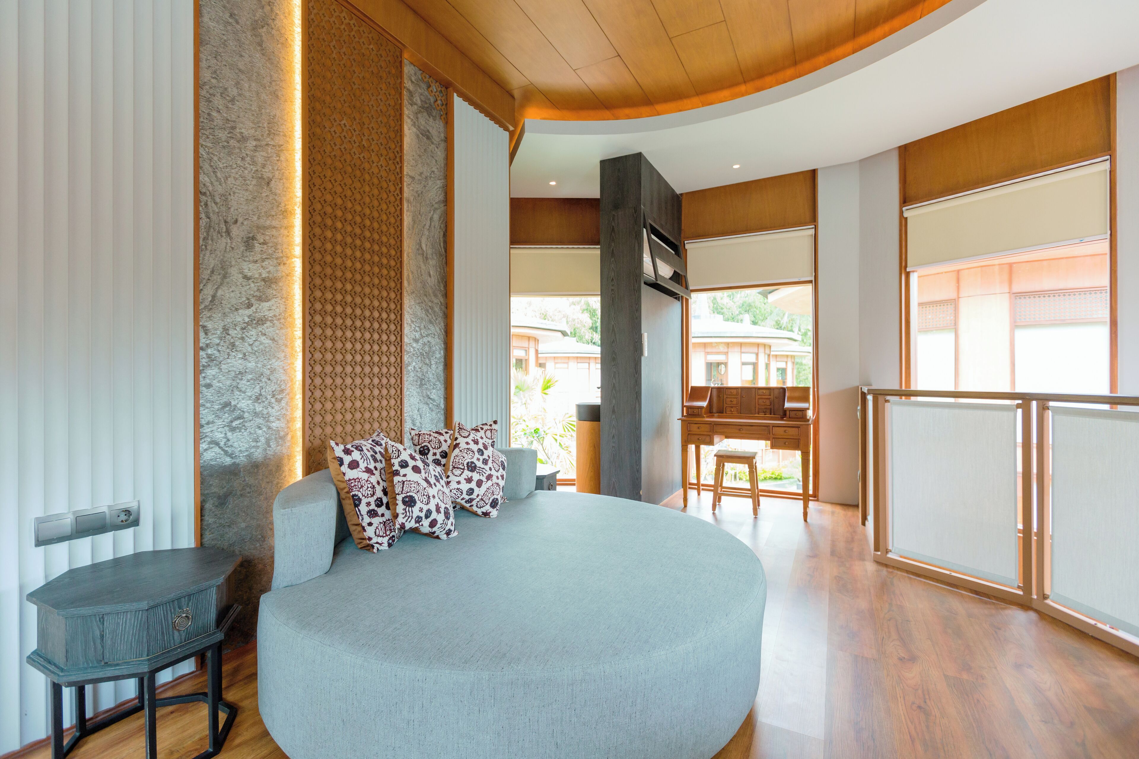 A modern living room with a curved sofa, a small table, and a view of the outside.
