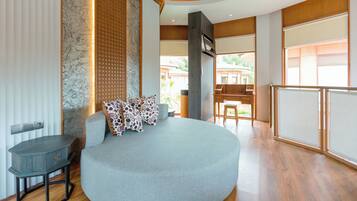 A modern living room with a curved sofa, a small table, and a view of the outside.