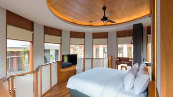 A modern hotel room with a large bed, a desk with a computer, a TV, and a balcony with a view.