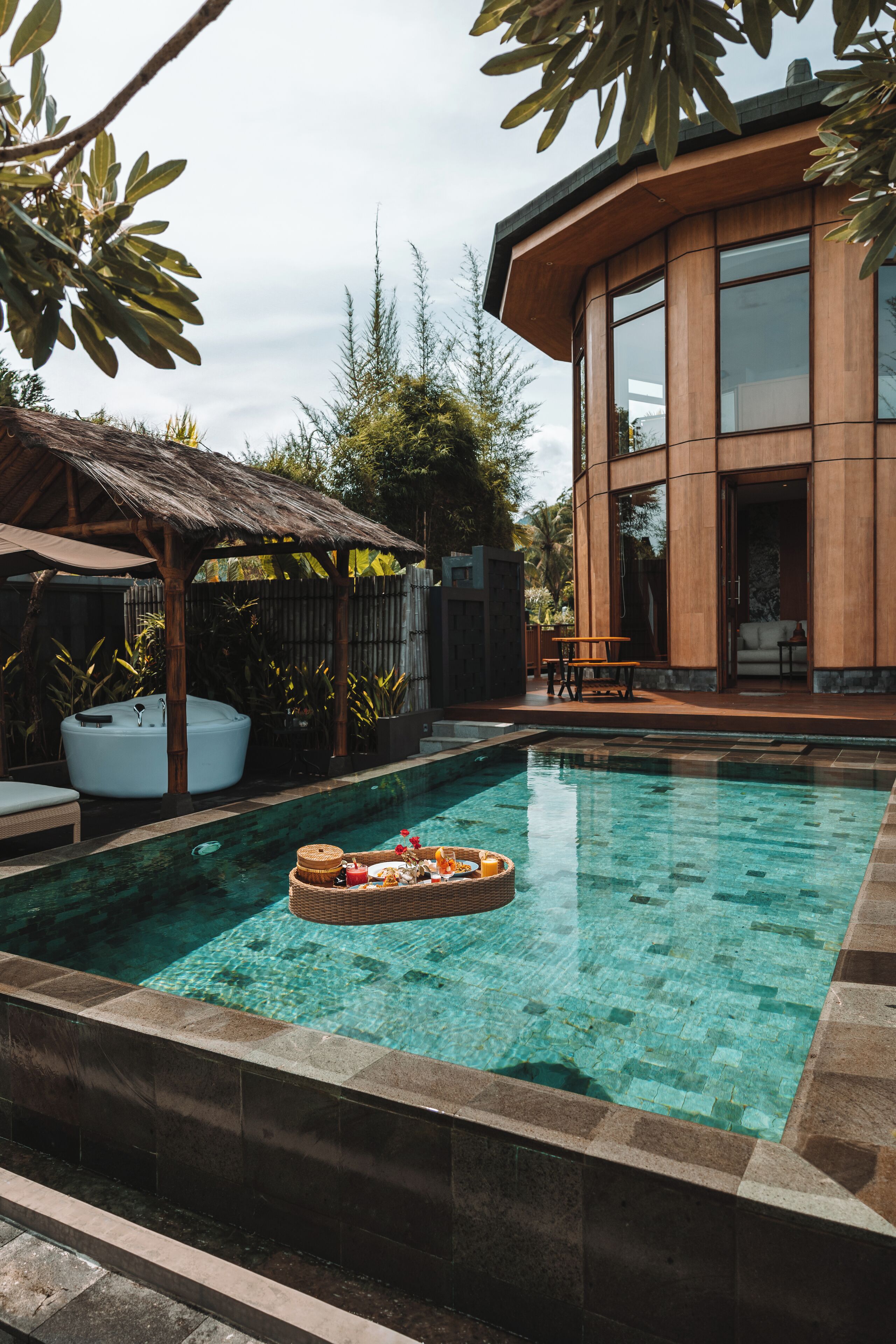 A modern pool area with a hot tub, a lounge chair, and a dining table.