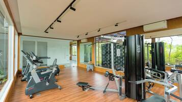 Un gimnasio con equipo de ejercicio, ventanas amplias y suelo de madera.