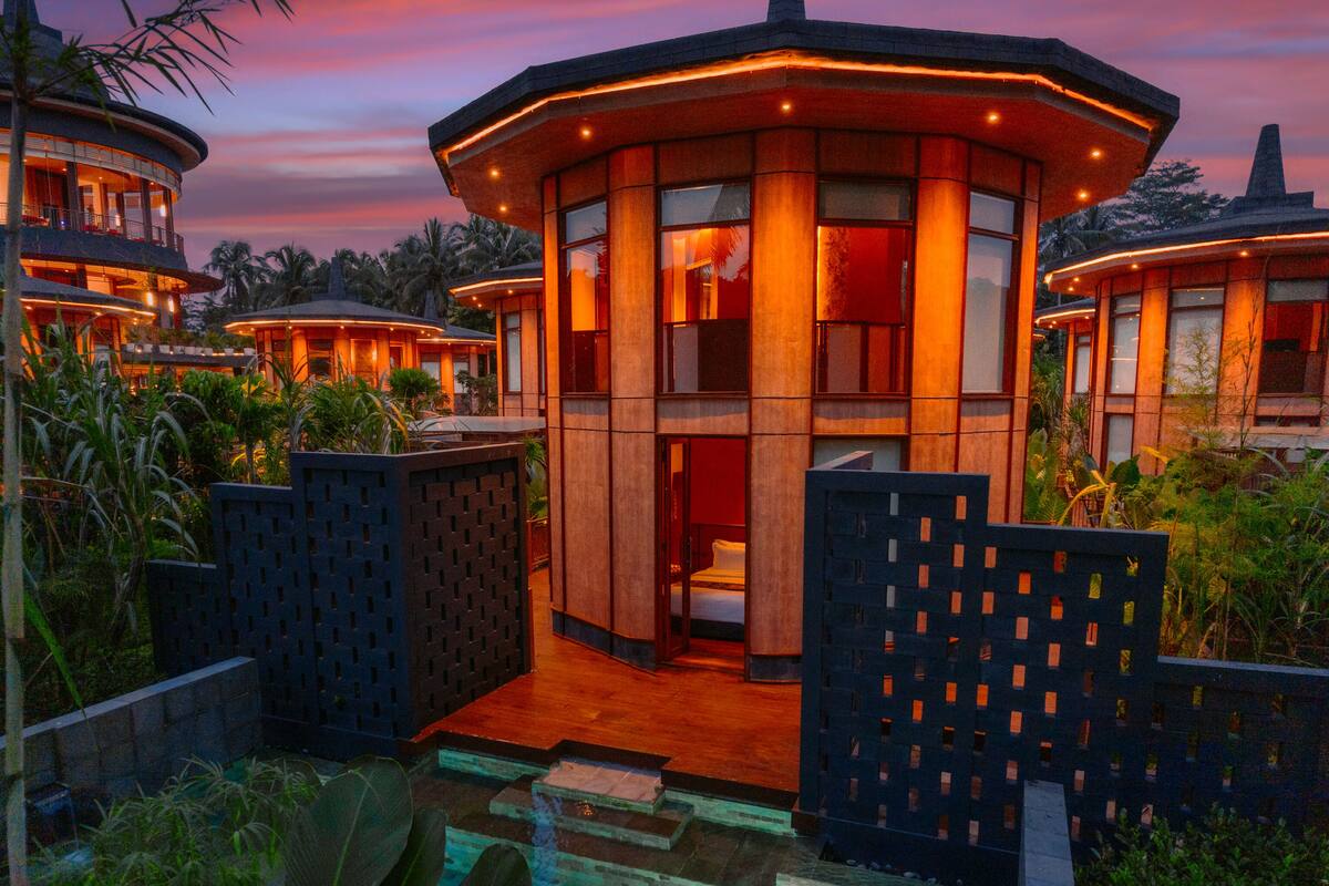 Un moderno resort con piscina, rodeado de exuberante vegetación y con arquitectura contemporánea.
