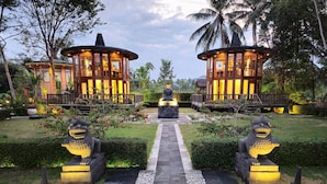 A resort with two wooden structures, a central Buddha statue, and stone lion statues. - Hotel Le Temple (Borobudur)