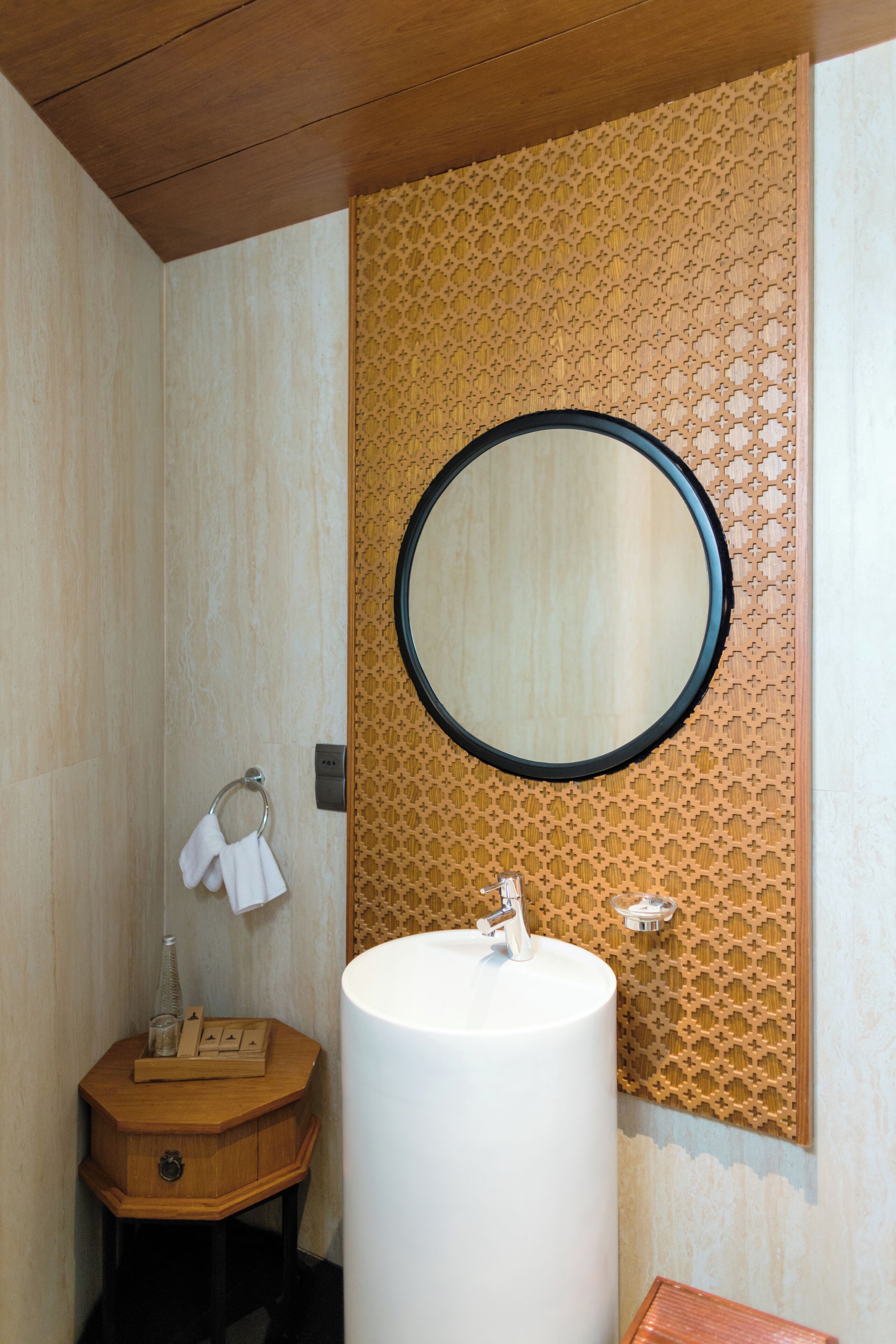 A bathroom with a wooden vanity, a large round mirror, and a white sink.