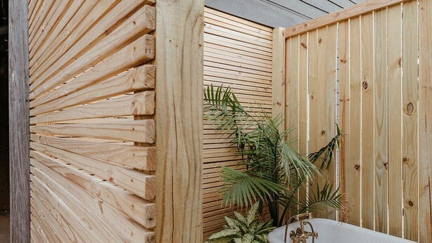 A wooden fence, a bathtub, and potted plants in a backyard. - The Haven • Outdoor Tub • Backyard Oasis • As seen on Magnolia Network (Kill Devil Hills)