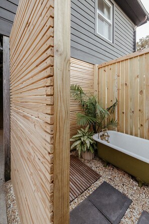 A wooden fence, a bathtub, and potted plants in a backyard. - The Haven • Outdoor Tub • Backyard Oasis • As seen on Magnolia Network (Kill Devil Hills)