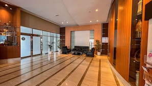 A spacious lobby with a marble floor, seating area with sofas, and a reception desk. - Cosmos Living Goldcrest Executive  (Dubai)
