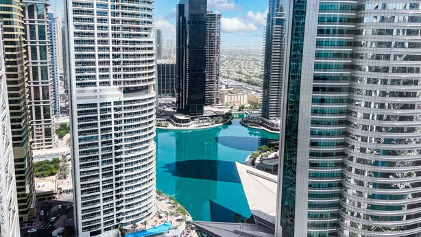 A high-rise hotel with a central courtyard and a pool. - Cosmos Living Goldcrest Executive  (Dubai)