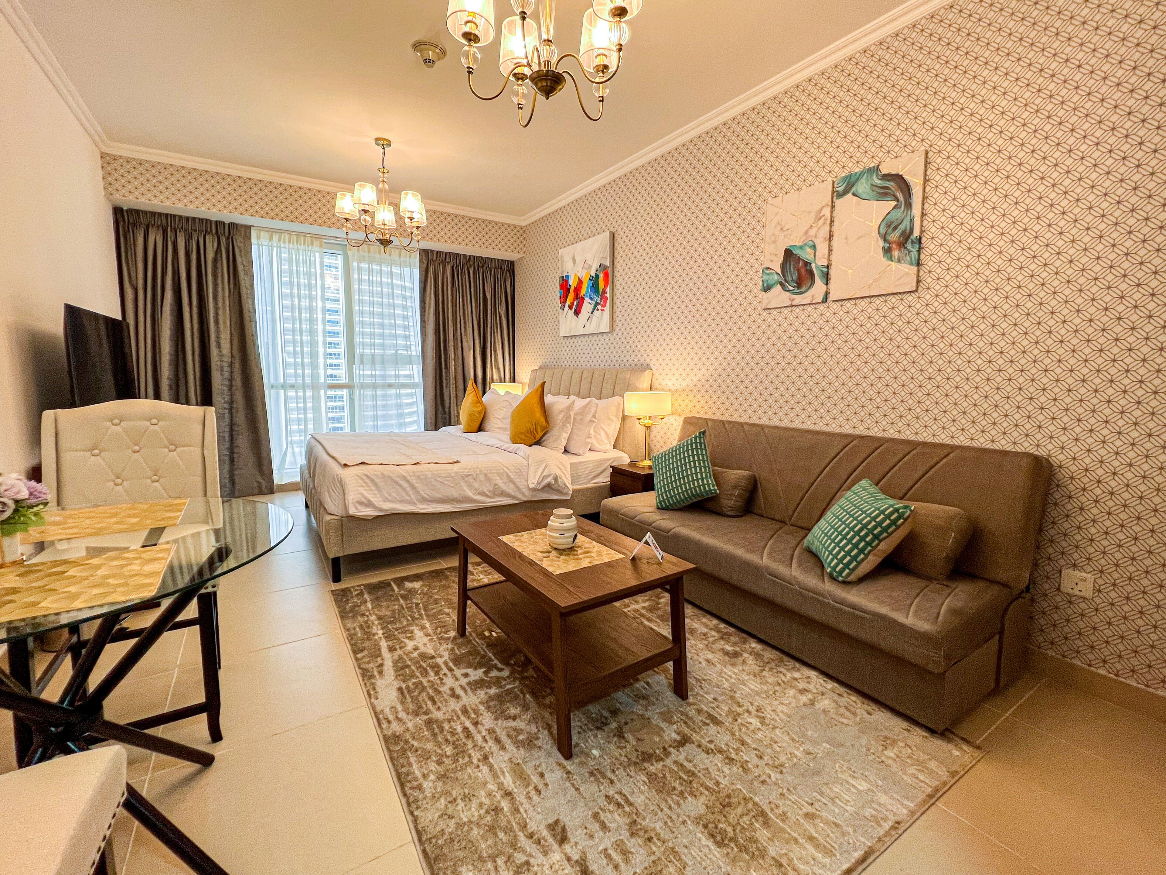 A hotel room with a bed, a sofa, a coffee table, and a TV.