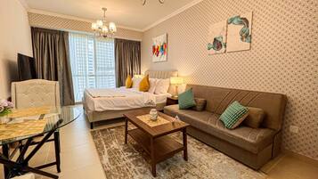 A hotel room with a bed, a sofa, a coffee table, and a TV.