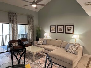 A living room with a sofa, chairs, a coffee table, and a ceiling fan.