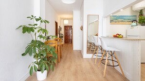 A modern kitchen with a wooden dining table, white chairs, and a fruit bowl on the counter. - Renovated apartment in Candelaria (CN)