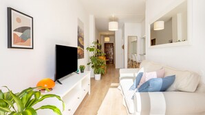 A modern living room with a flat-screen TV, a sofa with cushions, a coffee table, and a potted plant. - Renovated apartment in Candelaria (CN)