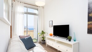 A modern living room with a sofa, TV, and potted plants. - Renovated apartment in Candelaria (CN)