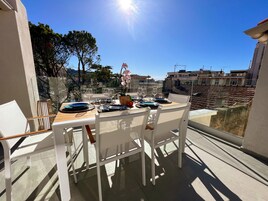 A balcony with a table set for dining, overlooking a cityscape with buildings and trees.