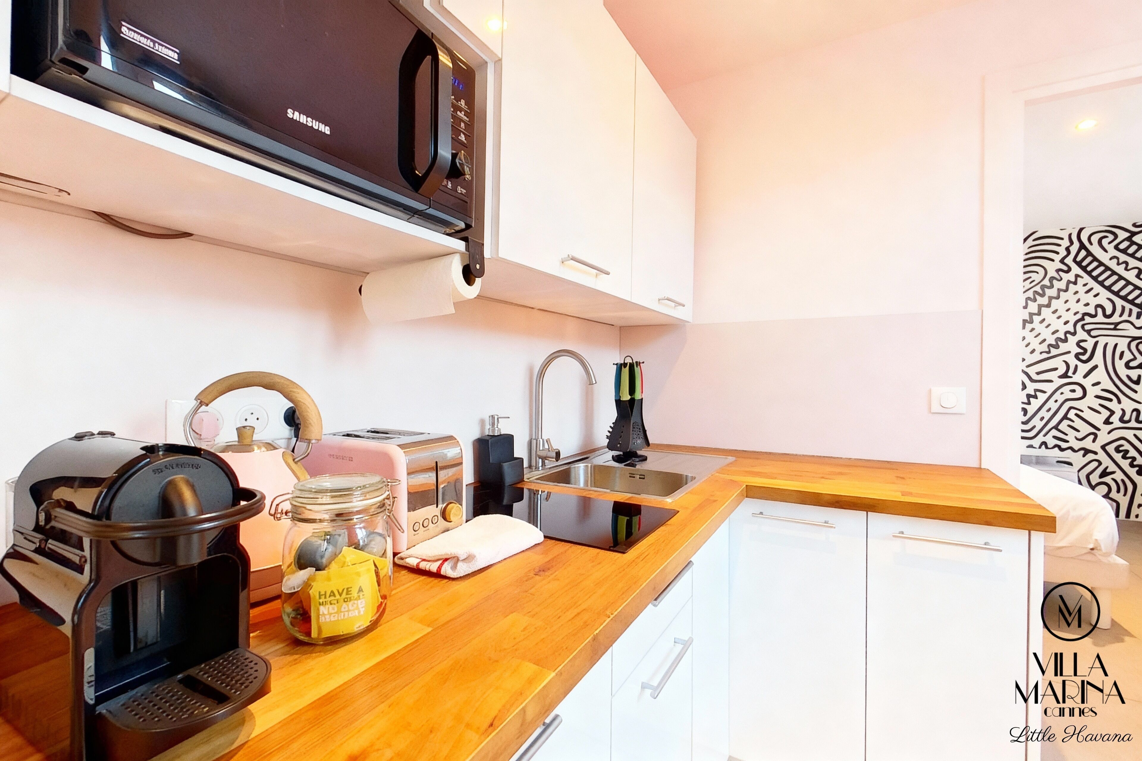 A modern kitchen with a microwave, toaster, kettle, and sink.