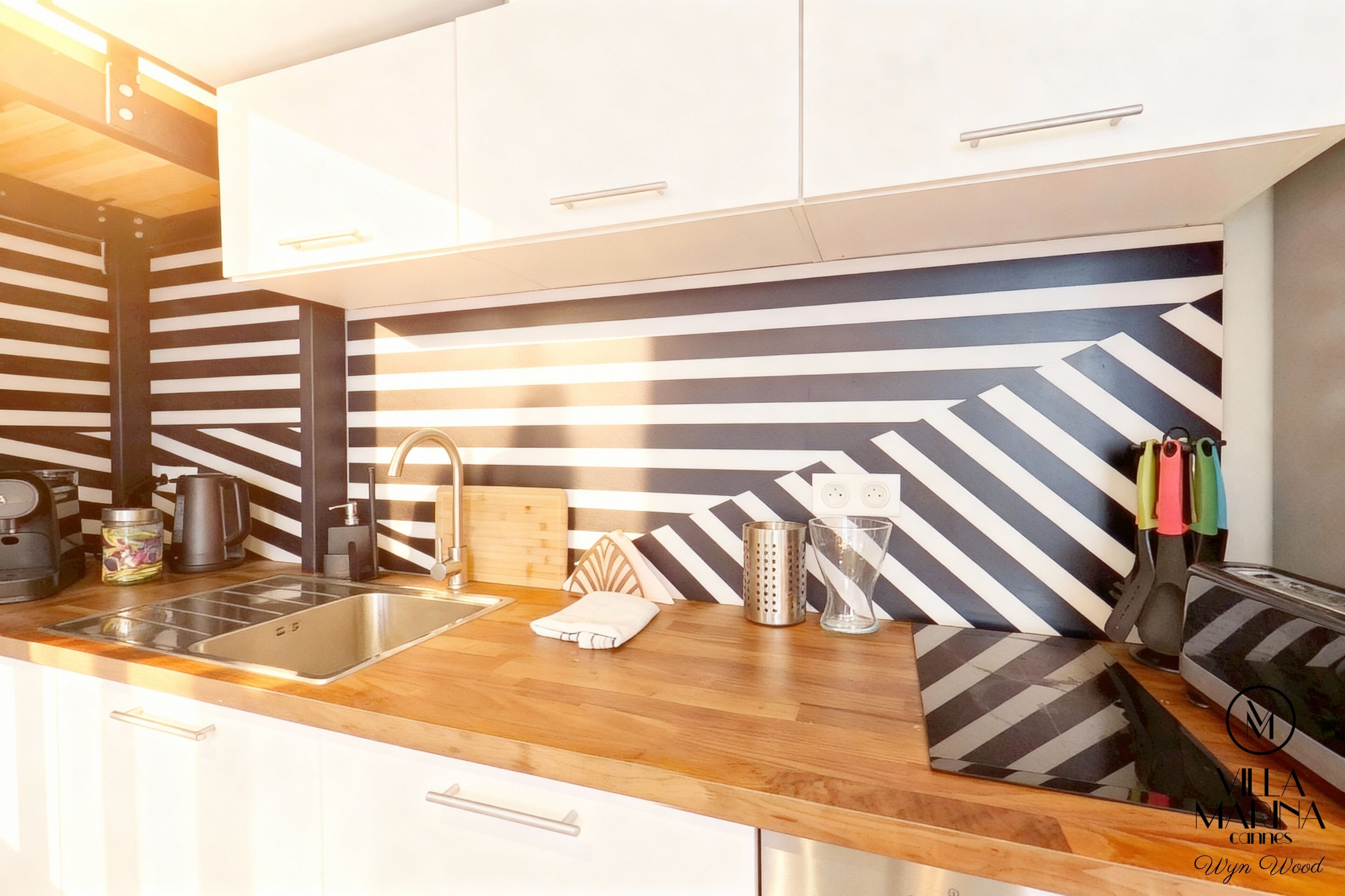 A modern kitchen with a striped backsplash, stainless steel appliances, and wooden countertops.