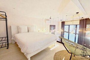 A modern bedroom with a large bed, a hanging chair, and a view of the city through large windows.